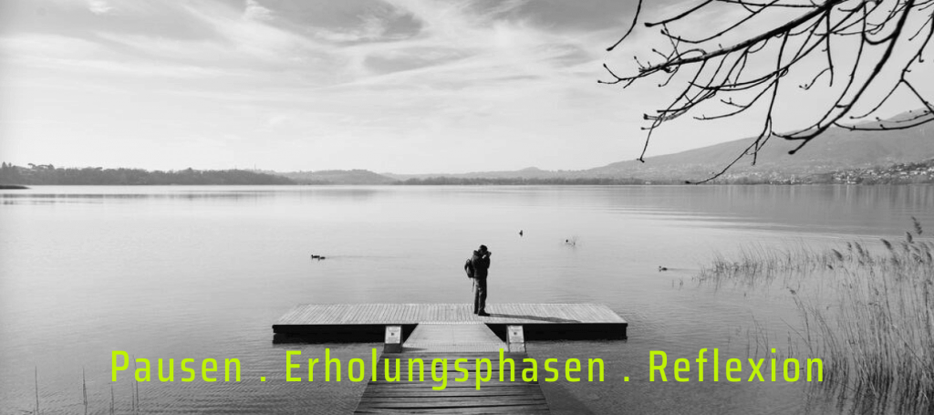 Photo mit einem Mann auf einem Steg an einem See. Aussage: Pausen, Erholungsphasen, Reflexion - auch das gehört zum Time-Blocking